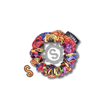 Load image into Gallery viewer, A small colourful scrunchie. A rose pattern in the colours of the pride flag. Red, orange, yellow, blue, green and purple. Approximately 8cm in Diameter.