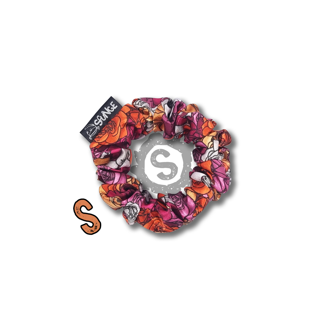 A small colourful scrunchie. A rose pattern in the colours of the Lesbian pride flag. White, orange and pink. Approximately 8cm in Diameter.